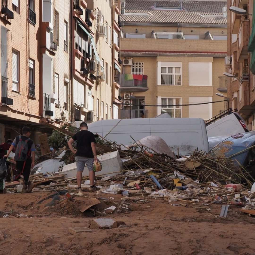 People walk through a debris-filled street after severe flooding in Valencia, Spain.