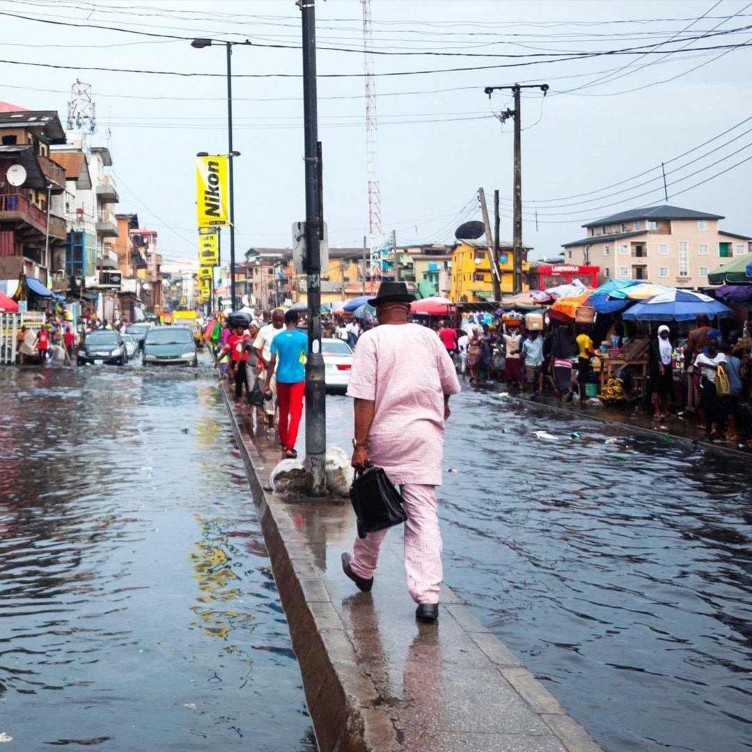 ''People walk down a heavily flooded market street in Lagos, Nigeria''