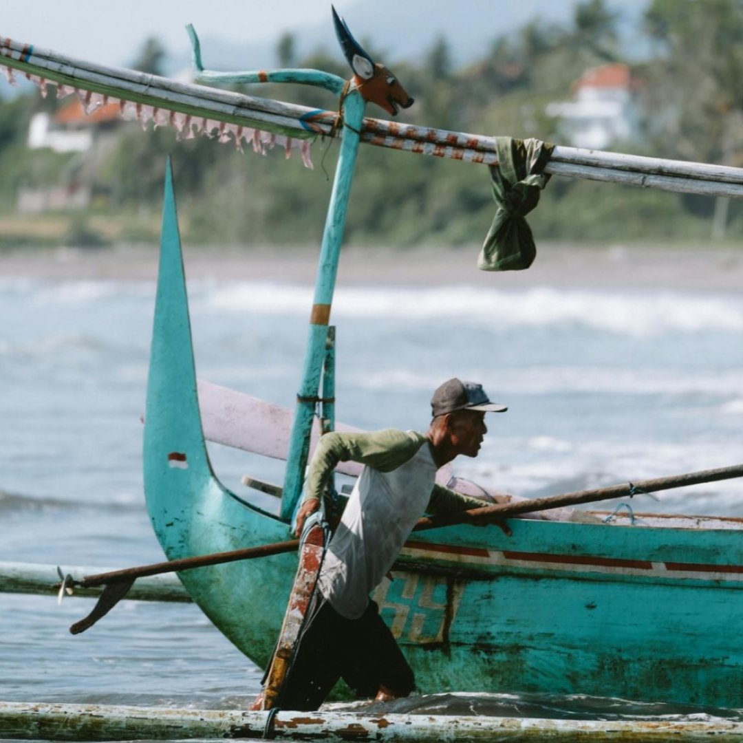 A man pushes a boat to shore in Bali, Indonesia