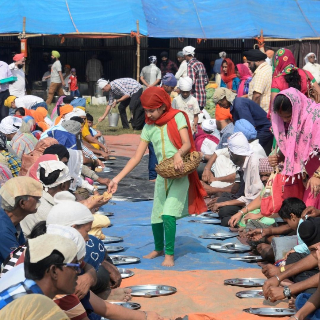 A young woman serves a free meal to people at a Sikh community kitchen