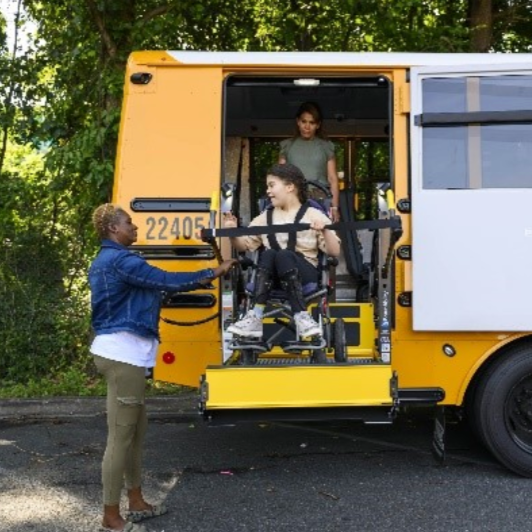 A girl in a wheelchair on a lift of a school bus