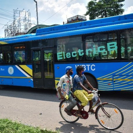 Bike riders pass next to an electric bus