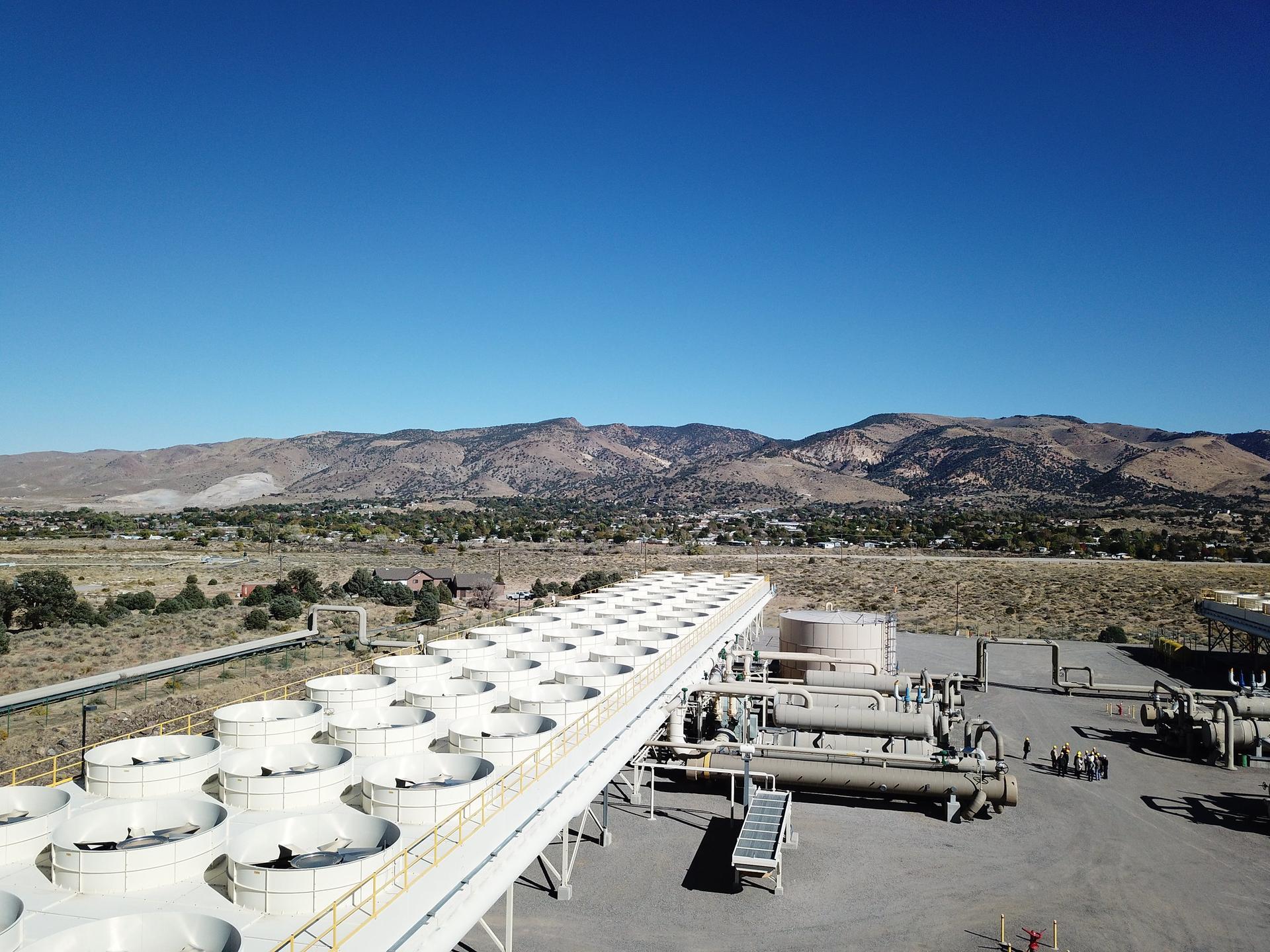 Aerial view of a large geothermal powerplant with mountains in the background.